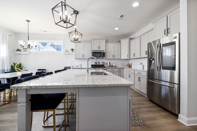 a kitchen with grey cabinets, white counters and stainless steal appliances
