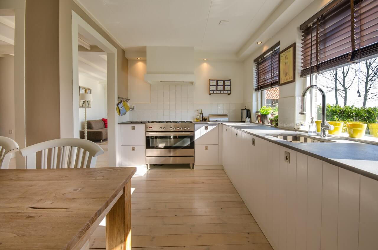 a kitchen with light wood flooring and white cabinets