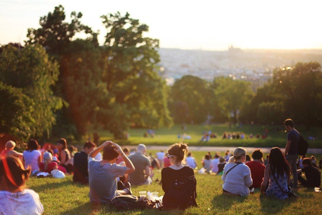 a large group of people gathering and sitting in a park
