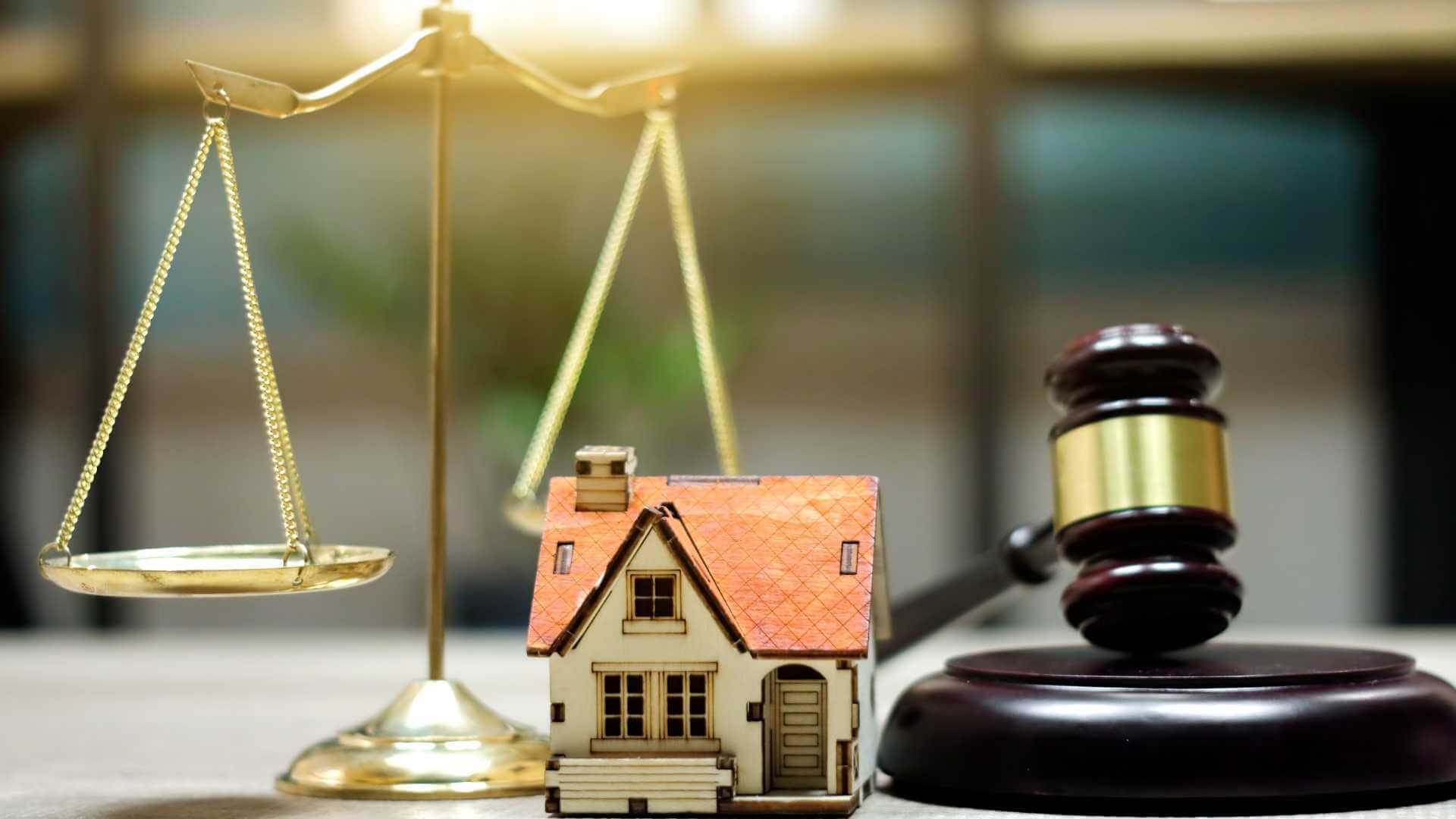 legal balance, judges gavel and house figurine on a desk
