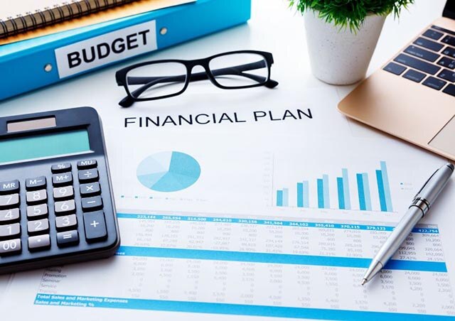 paper with financial plan written on it with graphs and charts a calculator pen glasses and laptop